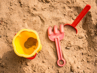 Bucket, puddle and rake in kid's sandbox top view