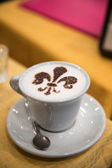 Cup of cappuccino coffee with a heraldic lily flower as a decoration