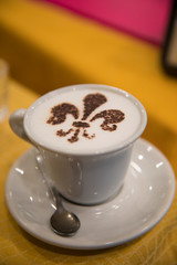 Cup of cappuccino coffee with a heraldic lily flower as a decoration
