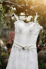 Bridal wedding dress hanging on the tree branch in the garden