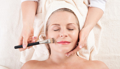 portrait of beautiful woman in spa environment. middle aged woman doing facial massage in a spa salon