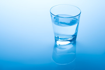 Glass of water on blue background