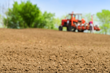 Farmer repairing tractor with seeder in field