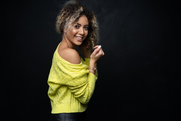 Portrait of a beautiful black female fashion model with curly hair over black background.