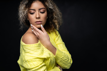 Portrait of a beautiful black female fashion model with curly hair over black background.
