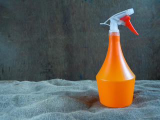 Orange spray bottle with a red handle on a gray background. Close-up.