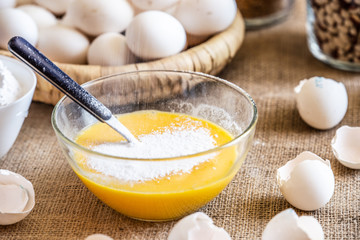 Add flour to a glass bowl with raw eggs.