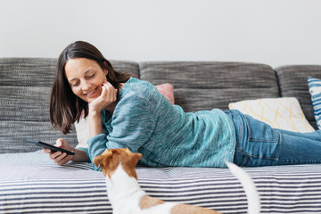 Happy woman relaxing on a sofa with her mobile