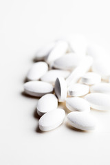 Fototapeta na wymiar Pile of white drug pills laying on white background.