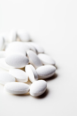 Fototapeta premium Pile of white drug pills laying on white background.