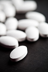 Obraz na płótnie Canvas Pile of white drug pills laying on black board background.