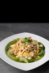 Fried cucumber with chicken egg in white dish on concrete table.