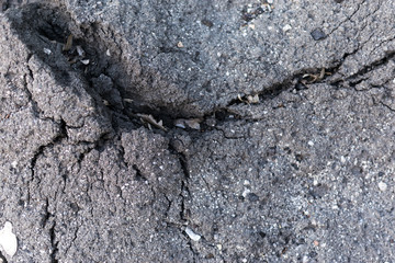 Old asphalt with cracks. The texture of the damaged pavement.