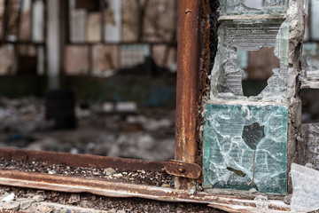 bullet-shattered glass window in an abandoned building