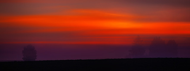 Morning red sunrise at mysterious landscape at the field