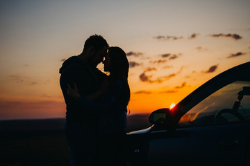 Silhouette kissing men and women at sunset in the car. A couple in love travels by car at sunset.