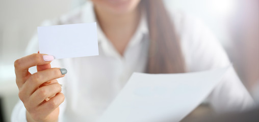 Female arm in suit give blank calling card to visitor closeup. White collar colleagues company name...