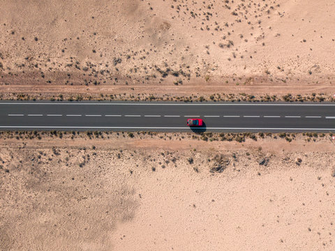 Aerial View Of A Red Car In The Desert Valleys Of The Island Of Lanzarote, Canary Islands, Spain. Paths And Roads