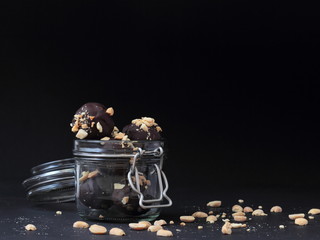 Closeup of vegan chocolates in a jar on black background.
