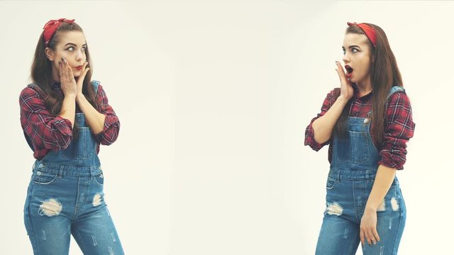 Wondered charming pinup girl in plaid red shirt with mouth opened, covered with hand, surprised to meet her copy, her clone.