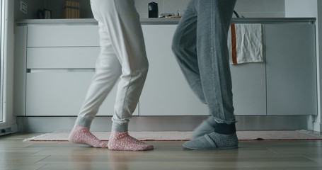 Close up of  young couple in pajamas are listening to music and dancing after morning coffee in the kitchen.
