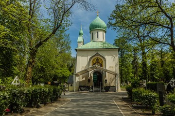 Fototapeta premium Prague, Czech Republic - May 8 2019: Orthodox church, the Sanctuary of the Dormition of the Theotokos at Olsany cemetery in Zizkov district. Fresh green colored trees, sunny day, blue sky.