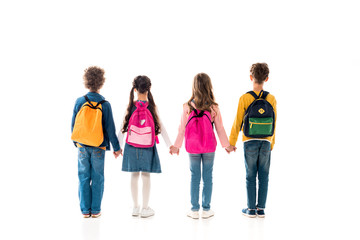 Fototapeta premium back view of schoolchildren with backpacks holding hands isolated on white