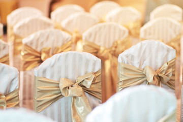 Beautiful chairs decoration with ribbon in wedding event hall, selective focus.