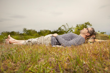 Mature man on trip in summer wilderness relaxing on meadow