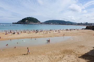 Fototapeta na wymiar Concha beach, San Sebastian, Spain. August 13,2014.View of Concha beach,a long beach north of Spain, with bathers walking on the sand
