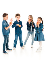 Obraz premium full length view of children in denim clothes eating apples on white