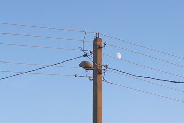 Air electrical wires on elecrticity reinforced concrete mast close up on blue sky background