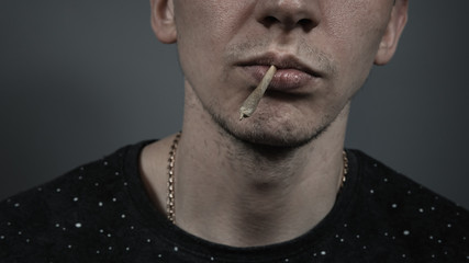 Fototapeta premium The young person smoking medical marijuana joint. Close-up.