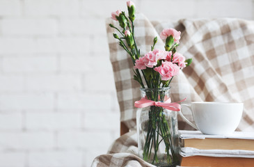 Home interior: flowers in vintage bottles, books and coffee mug close-up