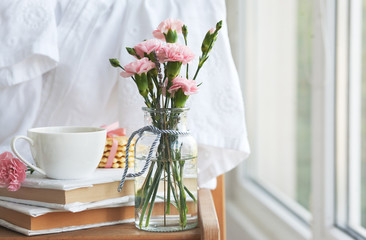 beautiful pink carnations in vintage bottles, coffee and cookies, closeup