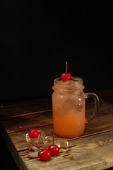 chilled lemonade in a glass with a cherry on a wooden background