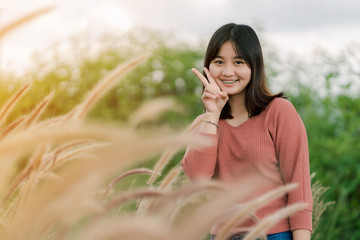 Asian woman Standing smiling in the fields of brown grass in the morning sun With a happy face