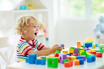 Kids toys. Child building tower of toy blocks.