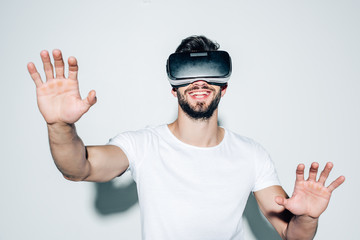 cheerful bearded man wearing virtual reality headset while gesturing on white
