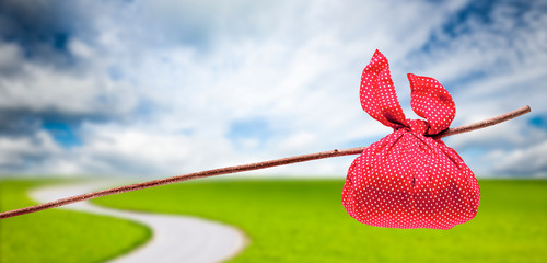 Rotes Wanderbündel am Stock in Landschaft