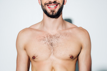 Fototapeta premium cropped view of cheerful and shirtless man smiling on white
