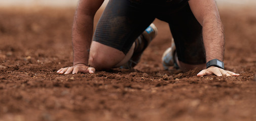 Mud race runners.Crawling,passing under a barbed wire obstacles during extreme obstacle race