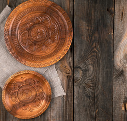 empty round brown carved decorative plate standing on a gray linen napkin, wooden gray background