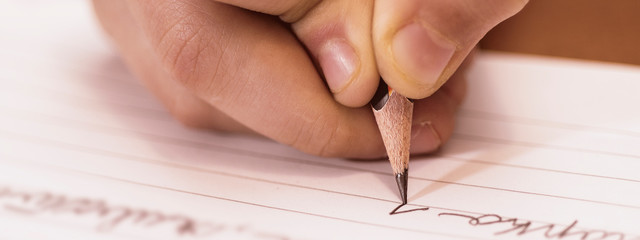 School Boy Writing Close Up. Pencil in Children Hand.