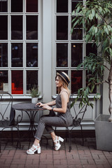 Beautiful girl drinks coffee in a city cafe. A girl in a straw hat