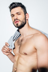 shirtless bearded man holding t-shirt while looking at camera on white