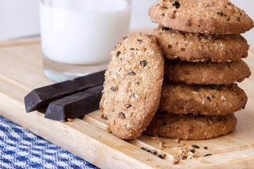 A stack of oatmeal cookies on the background of a glass of milk and chocolate bars