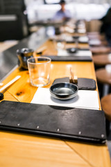 Interior of asian sushi Japanese restaurant in traditional style, wooden bar counter, menu, bowl, glass, napkin setting empty nobody vertical view of typical izakaya