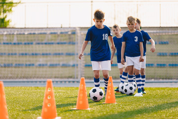 Soccer camp for kids. Boys practice football dribbling in a field. Players develop soccer dribbling...