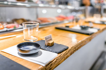 Japanese restaurant sign in traditional style, interior asian sushi wooden bar counter, menu, bowl, glass and napkin setting typical izakaya closeup